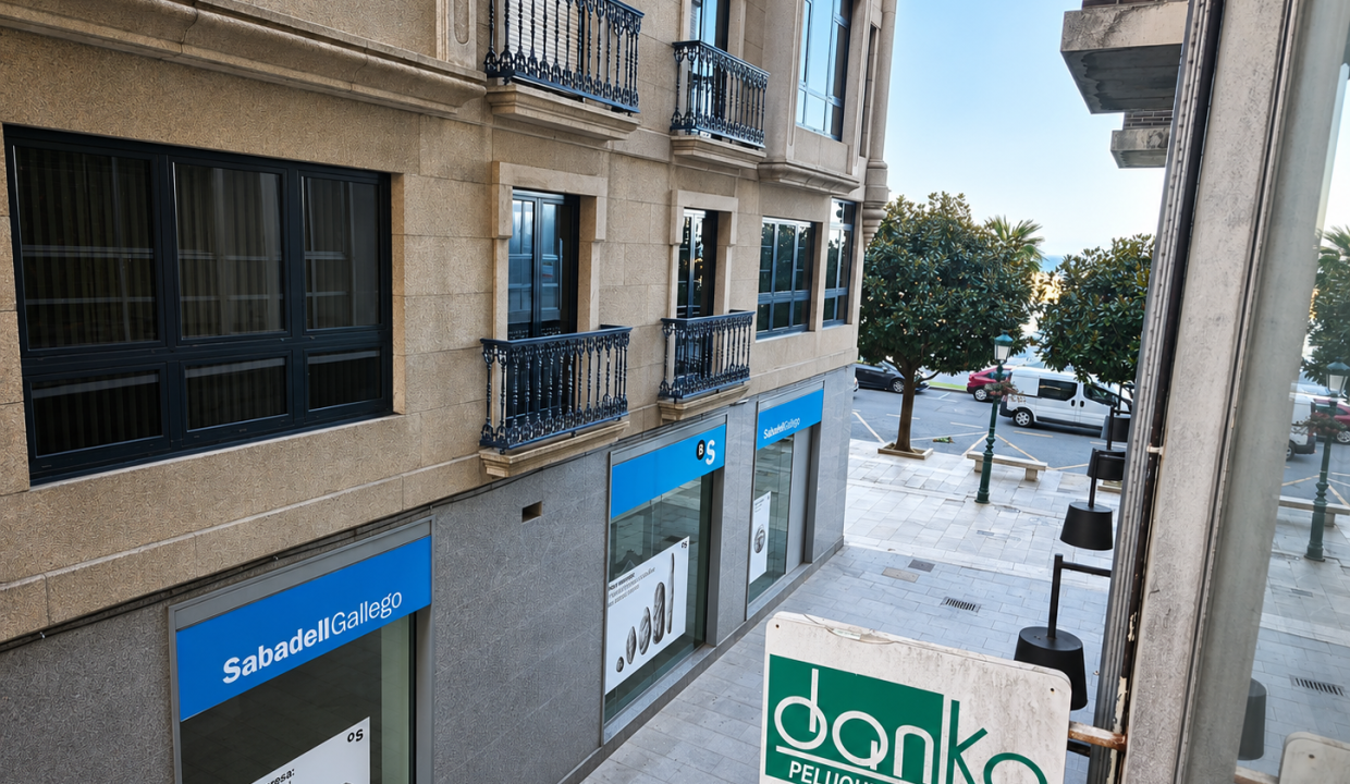 Vistas desde la primera planta de una vivienda en la calle Manuel Lustres Rivas, con edificios, comercios y calle del centro de Ribeira.